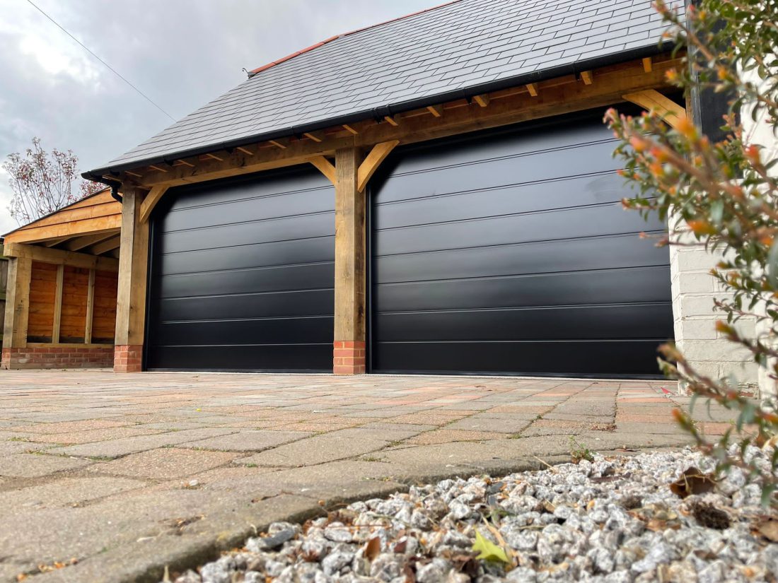 Double garage, side extension with sectional black garage doors.
