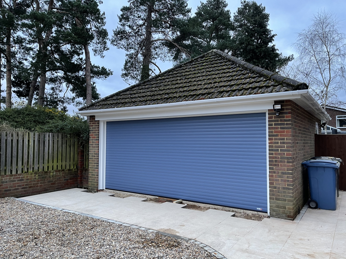 Detached garage building with light blue roller garage door.