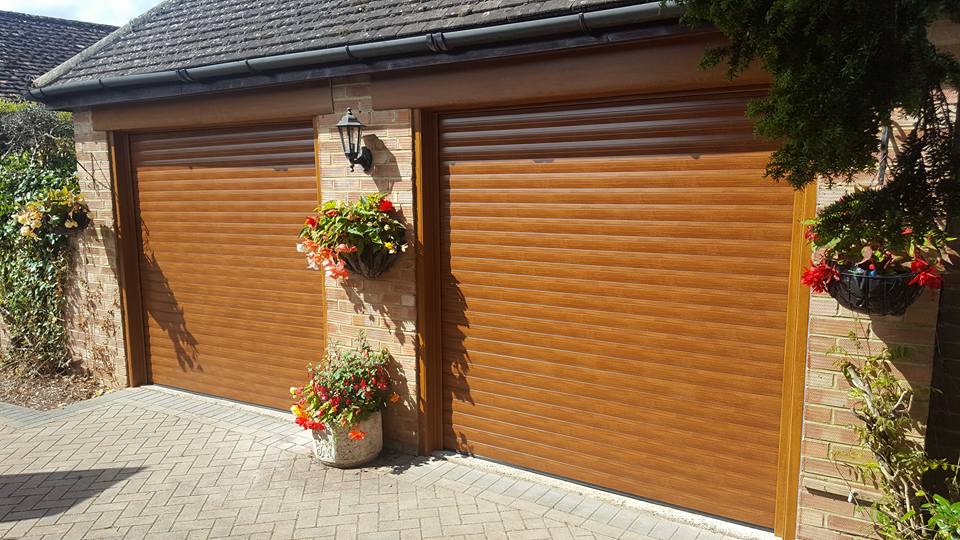 Attractive double garage with roller doors with wood effect design and lovely hanging baskets.