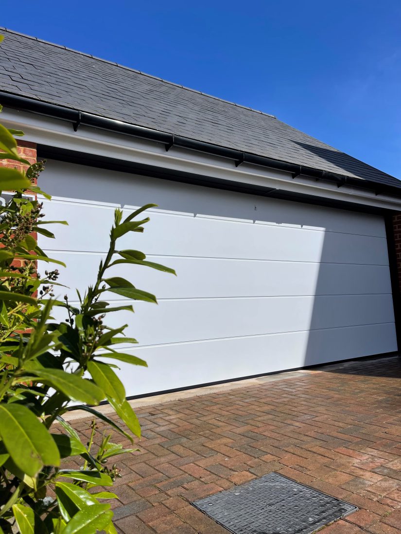 Detached garage building with sectional 2 in 1 door in white.