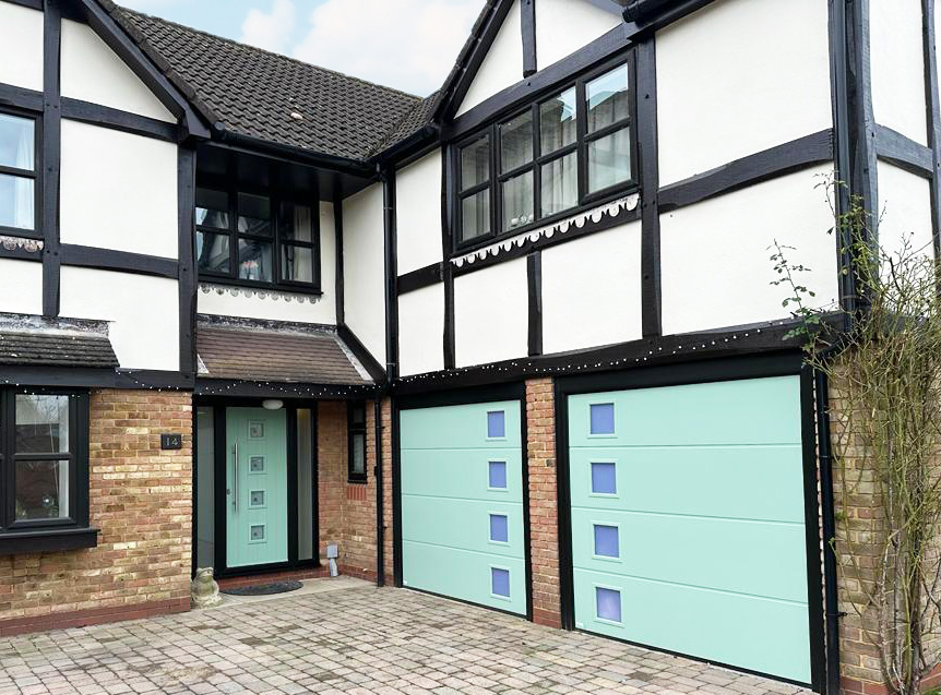 Matching composite front door and sectional double garage door with square consecutive windows.