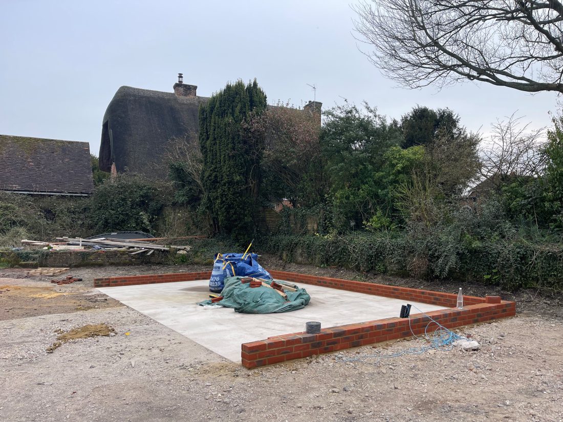 Foundations of a garage building with rubble bags in the centre.
