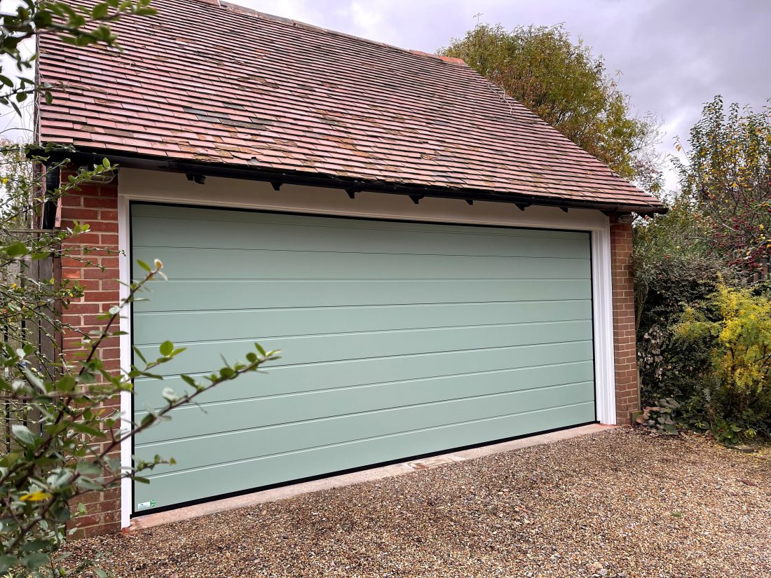 Detached garage building with sectional 2 in 1 door in Chartwell green.
