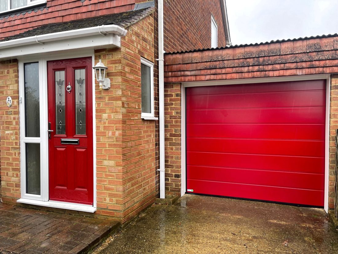 Matching ruby red sectional garage door and composite front door fitted by Skandoor.