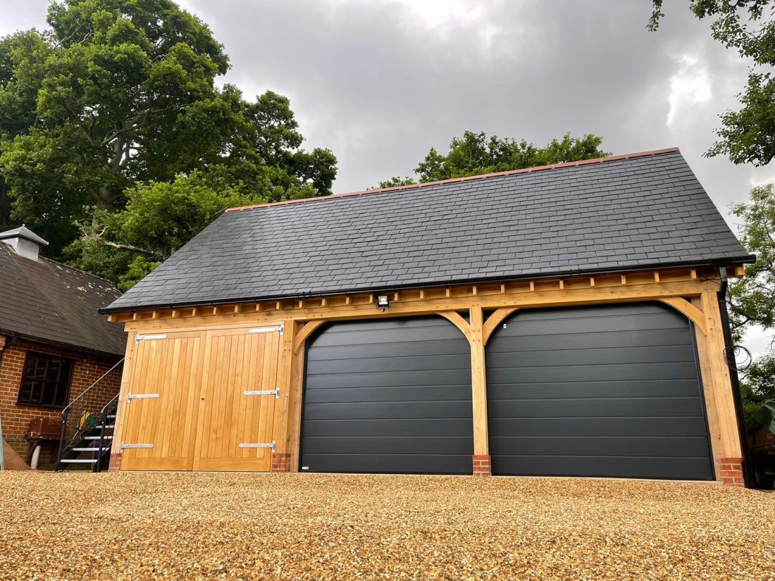 Detached garage with timber frame and black sectional garage doors.